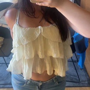 Ljusgul volangig linnetopp - Supersöt ljusgul linnetopp med flera lager volanger och tunna axelband. Toppen är croppad och har en luftig känsla. Köpt på vinted, står ej storlek men skulle säga Xs/S🥰