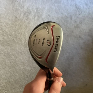 SPALDING SP99 Hybrid 4-21° - Spalding SP99 Hybrid 4-21° golfklubba i gott skick. Huvudet är hot forged och skaftet är grafit. Några mindre kosmetiska märken finns, men klubban är fullt funktionell och redo för spel. Perfekt för dig som vill ha en pålitlig hybrid till ett bra pris.