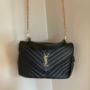 Svart quiltad YSL axelväska i skinn - Säljer min älsklings väska då jag har en ny nu! Den rymmer super bra och är en perfekt handväska att ha med sig! Självklart inte en äkta därav de bra priset! Super fint skick 