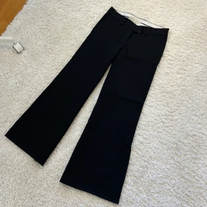 Lågmidjade svarta utsvängda kostymbyxor - Svarta Low waist kostymbyxor med utsvängda ben. Storlek S/34 och i bra kvalitet. 