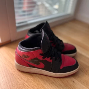 Nike Air Jordan 1 Banned Mid röd/svart - Säljer mina skor eftersom jag knappt använder de längre. Nypris= 1 499kr. Säljer de för långt pris för att jag inte vill ha de hemma liggandes. Skriv om du har frågor.