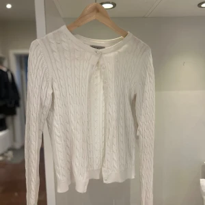 Vit kabelstickad kofta Basic You S - Använd få gånger, men som ny i skicket. Kabelstickad vit kofta från Basic You i ekologisk bomull. Klassisk modell med rund hals, knäppning framtill och långa ärmar. Perfekt för lager-på-lager och enkel att matcha med allt. Snygg ribbad kant vid ärmslut och nederkant. 🥰🥰