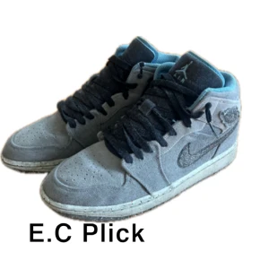 Jordan 1 mid cerater grey - Nike Air Jordan 1 Mid sneakers i grå mocka med svarta snören och blå detaljer på insidan. Klassisk Jordan-logga på sidan och broderad Swoosh. Mellanhög modell med rund tå och platt sula, perfekt för dig som gillar streetwear och ikoniska sneakers. Skriv vid funderingar!!!!!