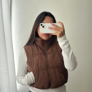 Brun dunväst från H&M  - Säljer en brun dunväst från H&M Divided i storlek XXS. Västen har hög krage, dragkedja framtill och två fickor på sidorna. Perfekt inför hösten 😊  Jag är vanligtvis str S, den passar mig bra oavsett om den är XXS. Skriv vid frågor 🥰