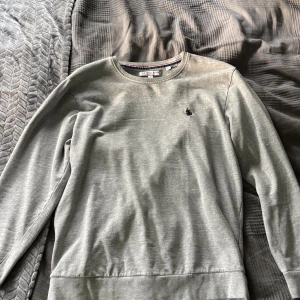 Grå sweatshirt från US Polo Assn i storlek M  - Säljer en stilren grå sweatshirt från US Polo Assn med rund halsringning och broderad logga på bröstet. Tröjan har långa ärmar och en klassisk passform som funkar till det mesta. Perfekt för dig som gillar enkel och snygg stil.