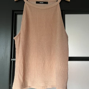 Glittrig rosa ärmlös topp Bik Bok - Supersnygg ärmlös topp från Bik Bok i rosa med glittriga trådar. Toppen har ribbad struktur och hög hals. Materialet är mjukt och stretchigt (den är liten i storleken)💕