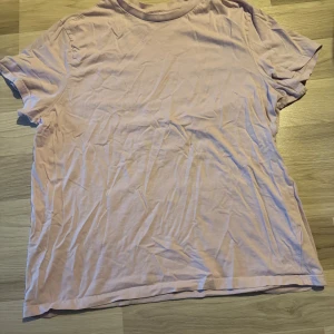 Ljusrosa t-shirt från H&M XL - En enkel och mjuk ljusrosa t-shirt från H&M i storlek XL. Modellen är regular fit med rund hals och korta ärmar. Tillverkad i bomull för skön känsla och avslappnad stil. Perfekt för dig som gillar basic och stilrena plagg.