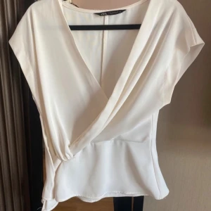Vit topp - Säljer en stilren vit topp från Zara i storlek XS. Perfekt för dig som gillar en clean och fräsch look. 
