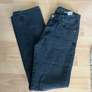Svarta low waist straight jeans från Bikbok - Svarta low waist straight jeans från Bikbok . Jeansen har fem fickor och är tillverkade i robust denim. Perfekta för dig som gillar en tidlös och clean look. Passar till allt och är riktigt snygga till sneakers eller boots. Färgen är lika överallt även om det framträder på bilden som att det är olika färger 