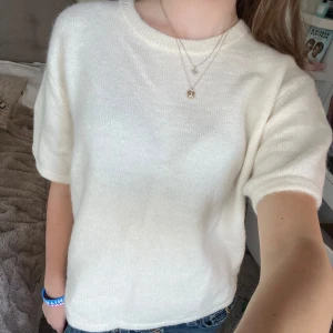 Vit stickad kortärmad tröja - Supermjuk och stilren vit stickad tröja  med korta ärmar och rund halsringning. Tröjan har en rak passform. Materialet känns fluffigt och lyxigt, och den neutrala färgen gör den lätt att styla. Aldrig använt 💗💗