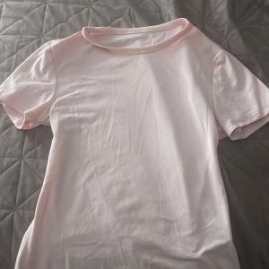 Ljusrosa basic t-shirt - Enkel och stilren ljusrosa t-shirt med rund halsringning och korta ärmar. T-shirten har en klassisk passform och är gjord i mjuk bomull, perfekt för en clean och avslappnad look.