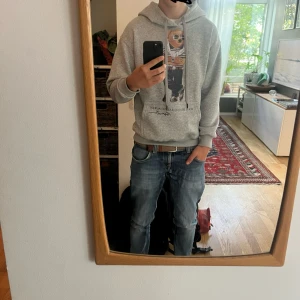 Grå polo bear hoodie  - Snygg grå hoodie från Polo Ralph Lauren med ikoniskt björntryck framtill. Insidan av tröjan har ett jätte skönt pälsliknande material, vilket gör tröjan perfekt att ha till hösten. Tröjan är helt ny med prislappen kvar. Jag säljer den då den tyävrr är för lite för mig. Skulle säga att den passar personer mellan 165-175. Kom privat om ni har fler frågor. Priset kan gå att diskutera. MVH Hugo 