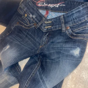 Mörkblå slim jeans från Esprit - Snygga mörkblå slim fit jeans från Esprit med slitna detaljer och kontrastsömmar. Klassisk femficksmodell med dubbla bälteshällor och broderad bakficka. Jeansen har en cool tvätt och passar perfekt till en avslappnad stil.
