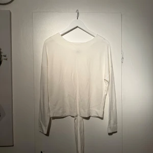 Vit omlottopp med knyt från Lindex - Säljer en stilren vit omlottopp från Lindex Toppen har långa ärmar och knytband i bak . 