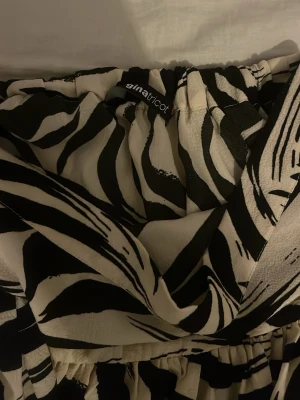 Zebramönstrad byxdress från Gina Tricot - Säljer en snygg byxdress från Gina Tricot med svartvitt zebramönster. Modellen har bred resår i midjan och voluminösa ben som ger en cool och trendig look. Materialet är mjukt och lätt, perfekt för dig som gillar att sticka ut.