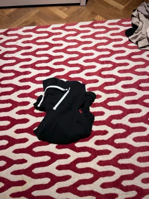 Svart hoodie  från Ralph Lauren - Svart hoodie från Ralph Lauren med vit snörning och röd logga broderad på sidan. Skön och stilrena, perfekta för chill eller häng. Mjukt material som känns nice mot huden. Skriv om du vill ha mer bilder.