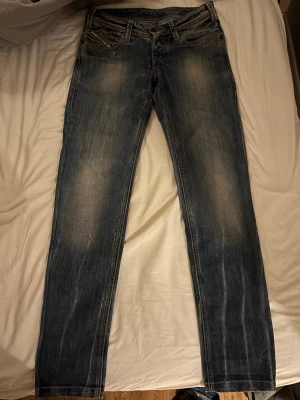Diesel Jeans, straight/slim fit.  - Säljer ett par Replay Anbass jeans i klassisk blå tvätt med snygga slitningar och raka ben. Jeansen har fem fickor, normal passform och är tillverkade i slitstarkt denim. Perfekt för dig som gillar en tidlös och chill stil.