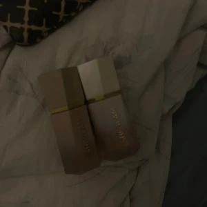 SHEGLAM duo av liquid contour & liquid highlighter  - Två produkter från SHEGLAM i snygga fyrkantiga förpackningar med guldiga detaljer. Ena är en sun sculpt liquid contour i färgen Terracotta och andra är en glow Bloom liquid highlighter i färgen Tea Cake. Highlightern är ganska använd och contourn är använd men inte som highlightern