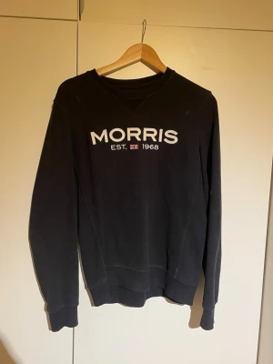 Svart sweatshirt från Morris, S - Svart sweatshirt från Morris i storlek S med broderad logga och brittisk flagga på bröstet. Tröjan har rund hals, ribbade muddar och är långärmad. 