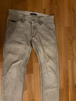 Ljusgrå jeans från Dolce & Gabbana - Snygga ljusgrå jeans från Dolce & Gabbana med klassisk femficksdesign och metallmärke bak. Jeansen har rak passform och är tillverkade i bomullsmaterial. Perfekt för dig som gillar stilrena och exklusiva plagg med italiensk touch.