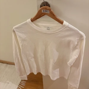 Vit långärmad topp från Brandy Melville - Säljer en enkel och stilren vit långärmad topp från Brandy Melville. Toppen har rund halsringning och är gjord i mjuk bomull. Passar perfekt till jeans eller kjol och har en normal passform med raka linjer.