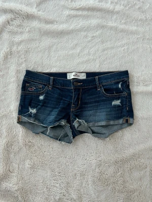 Hollister lågmidjade jeansshorts  - Ett par lågmidjade jeansshorts från Hollister i storlek W27, vilket motsvarar en vanlig S/M. Rakt över midjemått: ca 39cm. Jag fraktar inom 24h. Se liknande plagg i min profil!