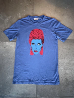 Blå David Bowie tröja - Säljer min gamla David Bowie tröja från John Richmond. Tröjan är köpt 2018 i London och är helt äkta. Tröjan är i nyskick (10/10), då det inte finns några spår av användning och storlek av tröjan är Medium (M). Skriv för fler bilder eller ifall du har några generella frågor. Priset kan diskuteras! 👍