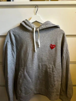 Comme des garcons hoodie  - Grå cdg play hoodie i bra skick. Köpt på NK (fler bilder som taggar etc kan skickas vid behov). Pris kan diskuteras vid snabb affär! 