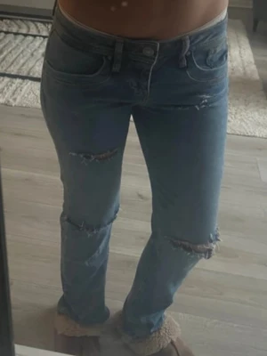 Blå jeans med slitna detaljer - Jättecoola jeans från LTB med fräcka hål på framsidan. Väldigt Low-wasited!! W27 & L30, se bild. Helt oanvända!!! Inga defekter! 