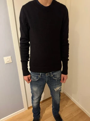 Svart stickad tröja från Acne Jeans - Säljer en svart stickad tröja från Acne Jeans i storlek S. Tröjan har rund hals, ribbade muddar och lång ärm. Enkel och stilren design som funkar till jeans eller andra favoritplagg. Perfekt för dig som gillar klassiska och snygga basplagg.