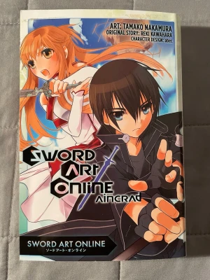 Sword Art Online: Aincrad - Sword Art Online: Aincrad är en spännande manga där spelare fastnar i ett VR-spel där döden är verklig. Med coola karaktärer och episka strider är detta ett måste för dig som älskar gaming, action och äventyr. Perfekt för dig som gillar manga och virtuella världar!
