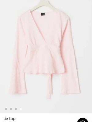 Ljusrosa omlottopp med knytband - Supersöt ljusrosa omlottopp från Gina Tricot med långa ärmar och v-ringning. Toppen har knytband i midjan som ger en snygg siluett. Priset kan diskuteras.