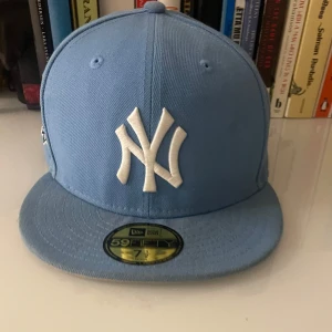 Blå New Era Yankees keps 59FIFTY - Säljer en ljusblå limited edttion New Era 59FIFTY keps  med New York Yankees-logga framtill och broderad 1999 World Series-patch på sidan.PRIS KAN DISKUTERAS VID SNABBA KÖP