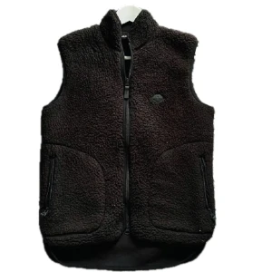 Svart fleeceväst från J.Lindeberg  - Mysig svart fleeceväst från J.Lindeberg i storlek XS. Västen har hög krage, två fickor med dragkedja och J.Lindeberg-logga på bröstet. Perfekt att slänga över en hoodie eller långärmad tröja när det är kyligt ute.