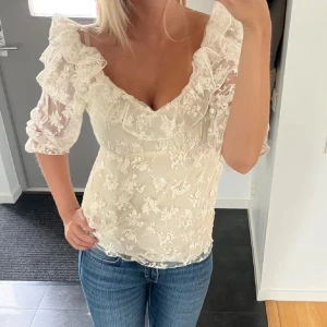  spetsblus med volangärmar - Superfin vit blus med blommig spets och v-ringning. Puffiga trekvartsärmar med volangdetaljer. Den är så fin men har tyvärr inte kommit till så mycket användning. Jag säljer den för att jag ska flytta och kommer inte ha plats med allt💕💕💕