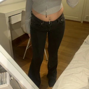 Svarta bootcut jeans låg midja - Säljer ett par svarta jeans med bootcut-modell och låg midja. Jeansen har klassisk femficksdesign och är i stretchigt denimtyg som sitter snyggt över höfterna och låren. Perfekta för dig som gillar en retro vibe och vill ha en bekväm passform.