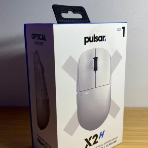 Pulsar X2H Size 1 - Pulsar X2H Size 1 är en trådlös e-sportmus med optiska brytare och PAW3395-sensor. Ergonomisk design för claw grip, låg vikt och snabb respons. Levereras komplett med USB-dongel och flätad kabel. Produkten ser ut att vara i nyskick utan synligt slitage.