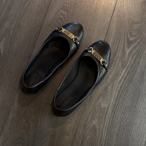 Svarta ballerinaskor med gulddetalj - Svarta ballerinaskor med gulddetaljer ifrån HM. Storlek 38, normala i storleken. Använda men inga defekter eller liknande! Hela och rena! 
