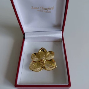 Lane Crawford guld blomma brosch - Unik brosch från Lane Crawford formad som en blomma i glansig guldton. Den har fem blad och en detaljerad mitt, perfekt för att ge din outfit en lyxig och cool touch. Kommer i original ask från Hong Kong.