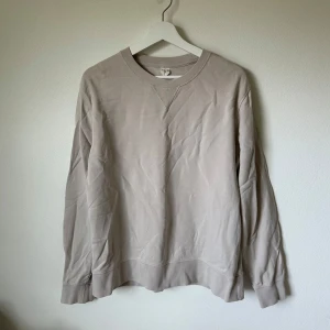 Beige sweatshirt från ARKET, M - En stilren beige sweatshirt från ARKET i storlek M. Tröjan har rund halsringning, långa ärmar och är tillverkad i mjuk bomull. Perfekt för en avslappnad look och enkel att matcha med andra plagg. 2J13