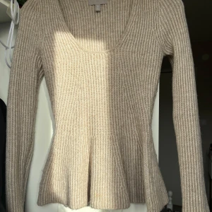 Beige ribbad stickad tröja H&M - Superfin beige stickad tröja från H&M med ribbat mönster och utsvängd nederdel. Tröjan har en djup rundringning och långa ärmar. Har används 3-4 gånger 