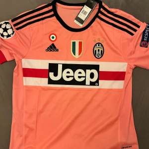 Pogba - Juventus 2015/2016 - Helt oanvänd/nyskick Paul Pogba Juventus bortatröja från säsongen 2015/2016. Den fina rosa färgen plus Pogbas otroliga säsong har gjort tröjan ikonisk bland dagens retrotröjor! Tveka inte med att höra av er för mer information eller frågor!
