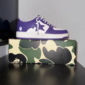 lila bapestas - Använt 4 gånger totalt. Säljer ett par BAPESTA sneakers i lila och vitt skinn. Klassisk siluett med stjärndetalj på sidan, perforerad tå och vita snören med metall-detalj. Kommer med originalkartong i camomönster. Perfekta för dig som vill sticka ut med streetwear.