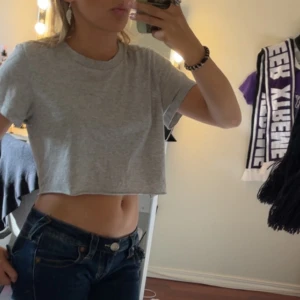 Grå croppad t-shirt i bomull - Enkel och stilren ljusgrå croppad t-shirt med rund hals och korta ärmar. T-shirten är i mjuk bomull och har en loose fit som ger en avslappnad vibe. Perfekt till jeans eller shorts för en chill look.