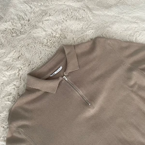 Beige halvzip tröja från Zara - Säljer en stilren beige långärmad tröja från Zara med krage och halv dragkedja framtill. Tröjan är i mjukt stickat material och har en klassisk, clean look som passar perfekt till jeans eller dressade byxor.
