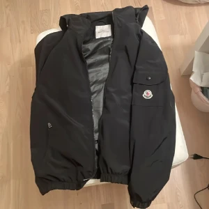 Svart Moncler dunjacka med huva - Säljer en svart dunjacka från Moncler. Fungerande scan på loggan och bara använd några gånger.  Rep!!!!! Pris kan diskuteras 