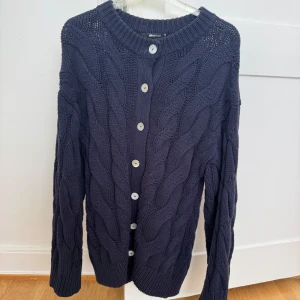 Mörkblå kabelstickad kofta Gina Tricot - Kabelstickad mörkblå kofta från Gina Tricot med stora vita knappar framtill. 