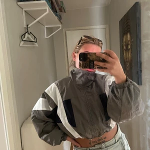 Gråvit vindjacka från Bershka - Säljer en grå och vit vindjacka från Bershka i storlek M. har dragkedja framtill och har inslag av reflexer. Perfekt för hösten!                                            (Läs alltid min profil för villkor)
