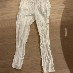 Vita linnebyxor med smal passform - Snygga vita linnebyxor med smal passform och klassisk midja. Byxorna har fickor i sidorna och bälteshällor, perfekta för en fräsch och stilren look. Lätta och luftiga, perfekta för varmare dagar. Dom är bara ostryckta och därför så rynkiga men väldigt sköna och passar bra.