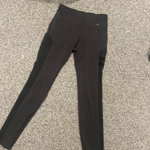 Svarta höga leggings med paneler  - Svarta leggings med hög midja och snygga paneldetaljer längs sidorna. Tight passform och stretchigt material som passar perfekt till träning eller chill. Stilrena och enkla att matcha med det mesta.